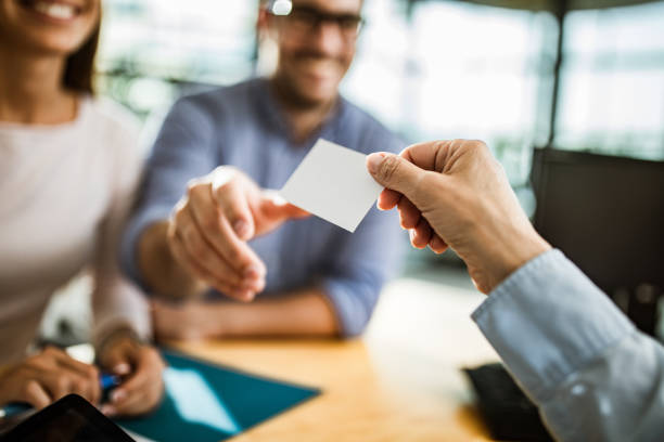 Close up of unrecognizable agent giving her business card to a couple. Copy space.